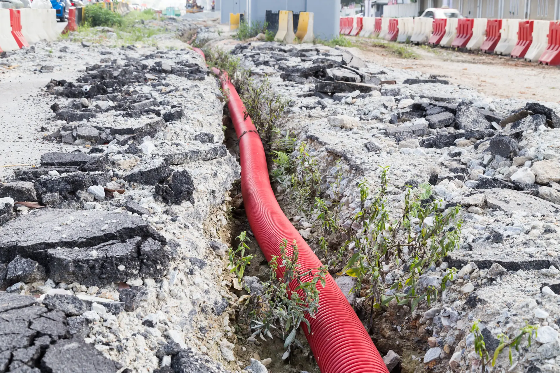 The image shows Rhino Rooter repairing an underground sewer pipe, with barriers set up to keep the area safe.