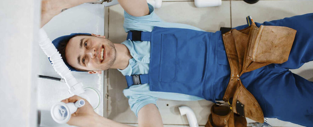 A Rhino Rooter plumber is ready to fix pipes under a sink in West Haven, Utah.