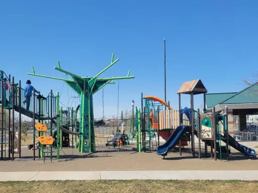 Children are playing at a playground while a Rhino Rooter plumber works on pipe replacements and sewer repairs close by.