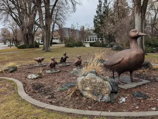 A park displays a bronze duck statue leading ducklings, offering a peaceful spot for Rhino Rooter plumbers to unwind after work.