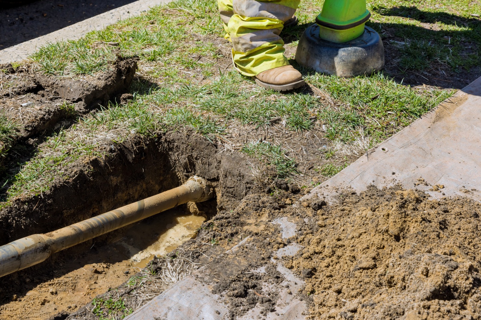 A Rhino Rooter worker stands by a dug-up pipe, prepared to replace or fix underground sewer lines.