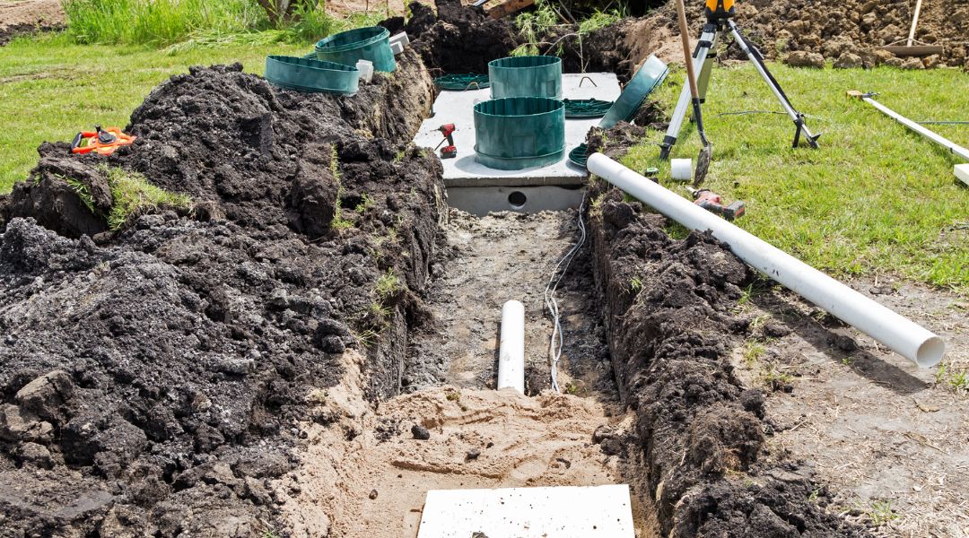 A Rhino Rooter technician works on installing a new septic tank system, making sure pipes are replaced and sewer repairs are done safely.
