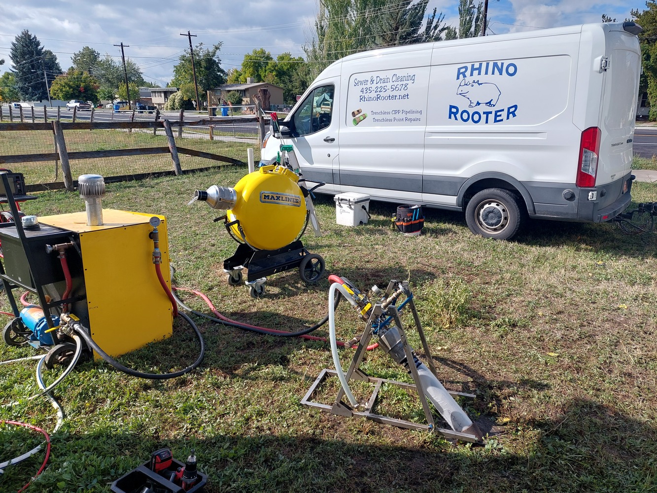 A Rhino Rooter van is parked by the road with plumbing tools ready for sewer and pipe repair. The scene shows a trusted plumber at work.