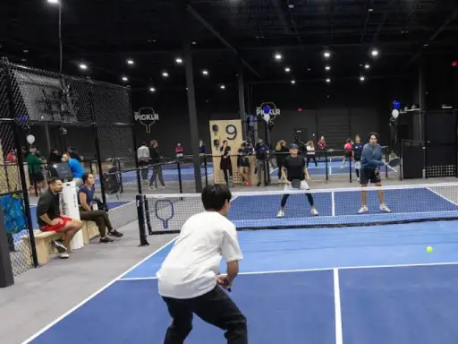 People play pickleball on indoor courts. The area is clean and safe after Rhino Rooter fixed the pipes using new methods.