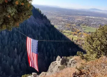 An American flag hangs over a valley, showing the pride and dedication Rhino Rooter brings to serving local communities.
