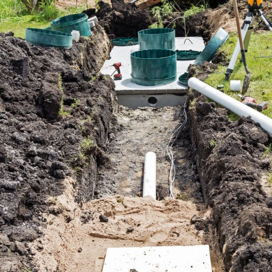 A Rhino Rooter technician works on installing a new septic tank system, making sure pipes are replaced and sewer repairs are done safely.
